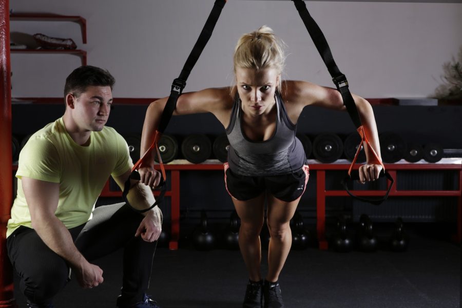 Personal trainer crouched beside person working on fitness levels, success tips