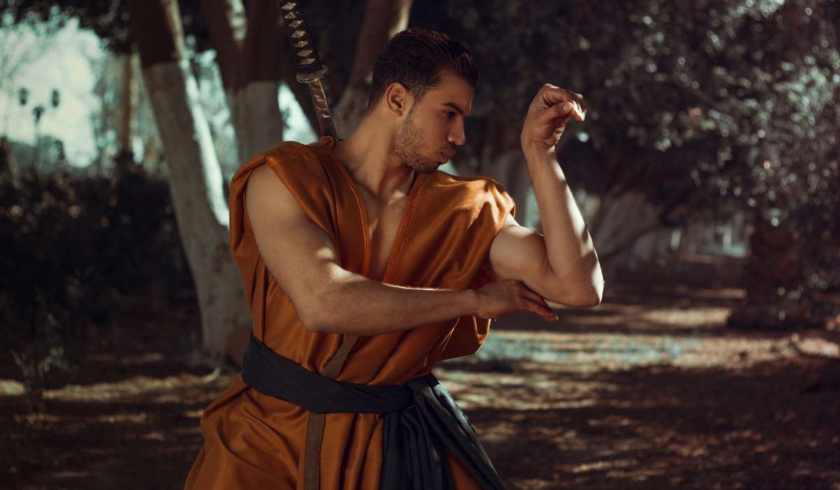 Robed martial artist posed outside among trees