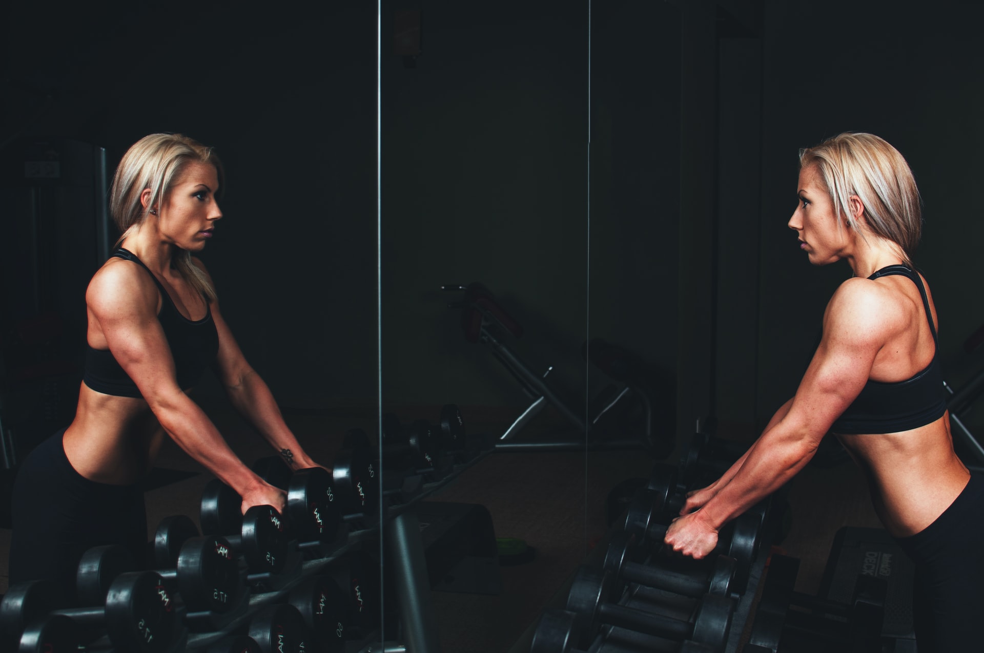 weightlifter looking in the mirror, holding dumbbells