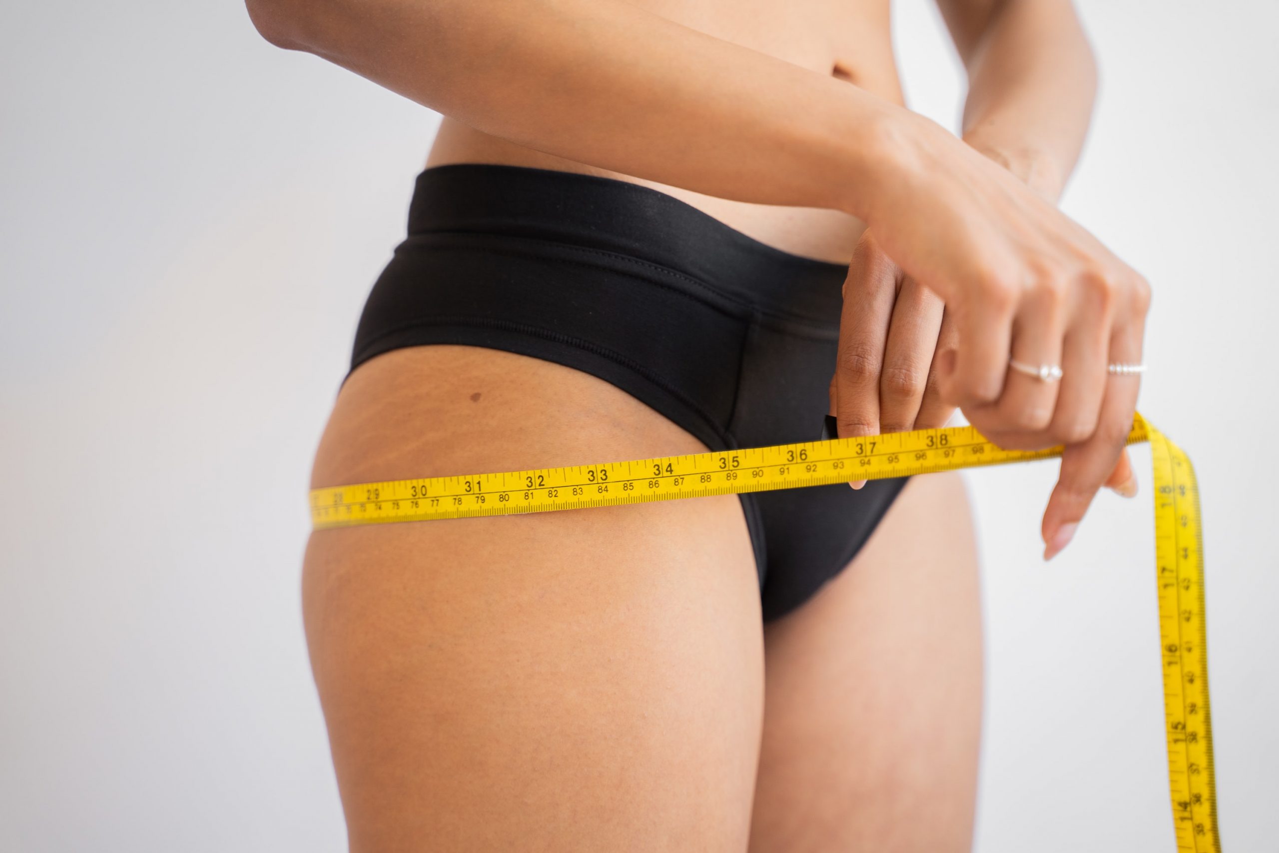 Woman in underwear using measuring tape