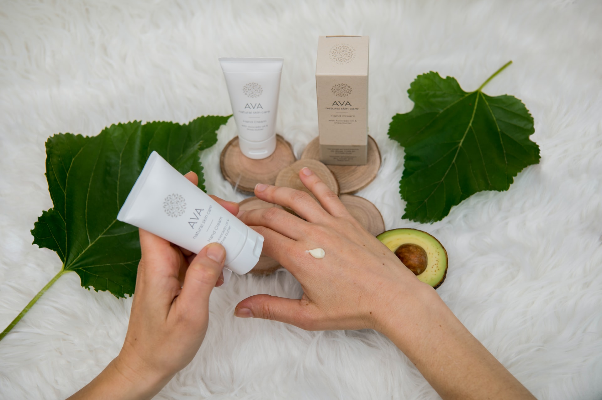 closeup of hands applying skincare product above a selection of skincare products