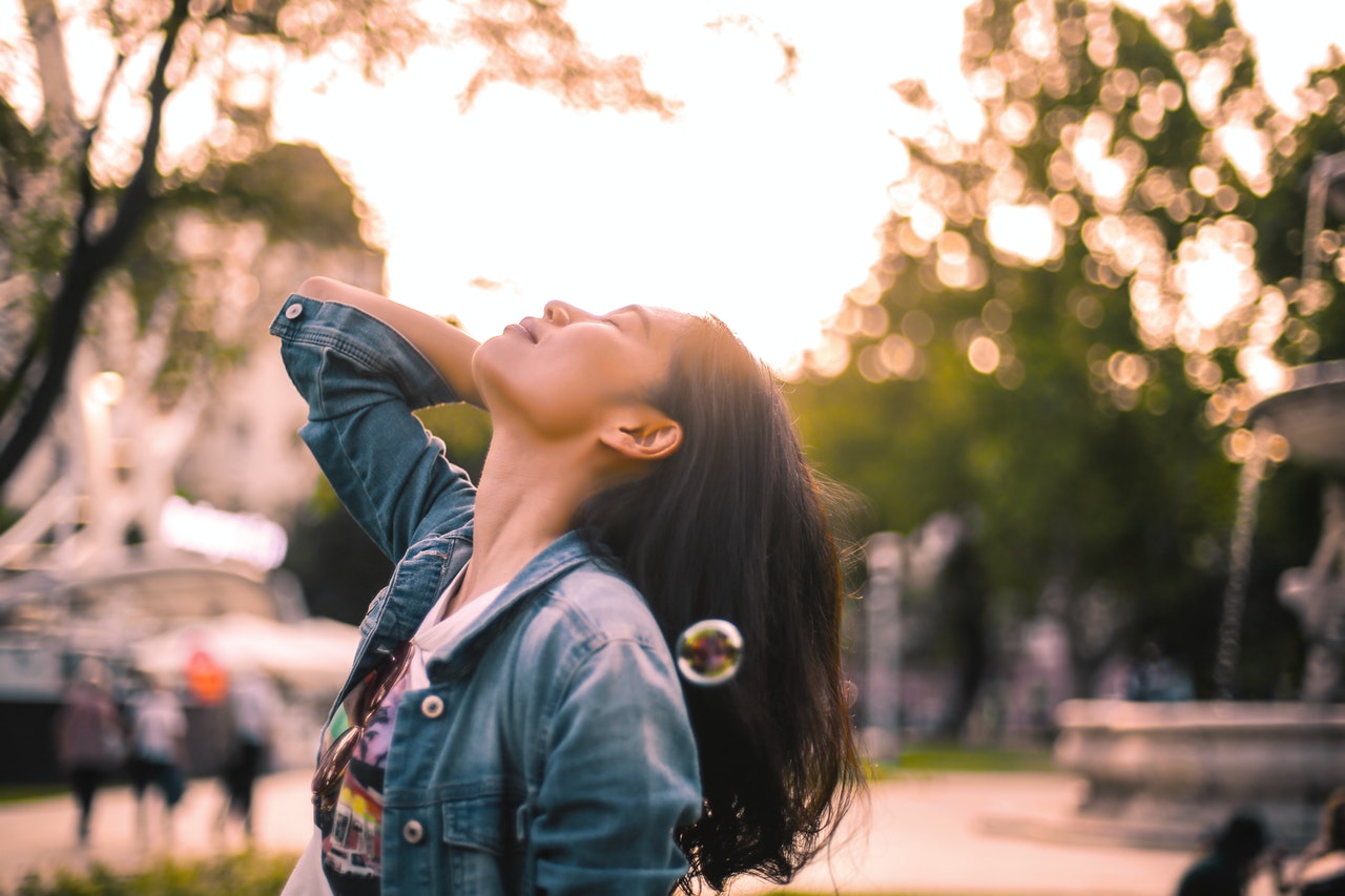 happy person outside looks up to autumn sky, hand behind head, healthy skin this autumn