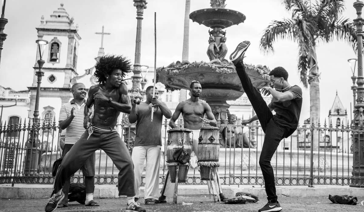 Black and white photo of two people doing capoeira outside
