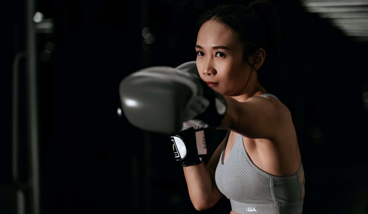 Person wearing boxing gloves throwing a jab, black background