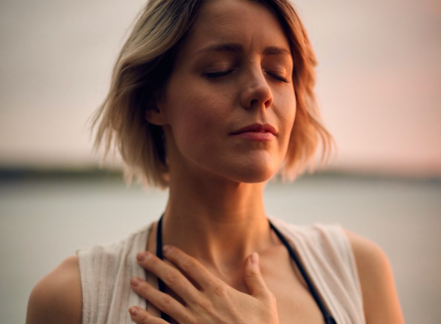 person in setting sunlight, eyes closed, hand on chest