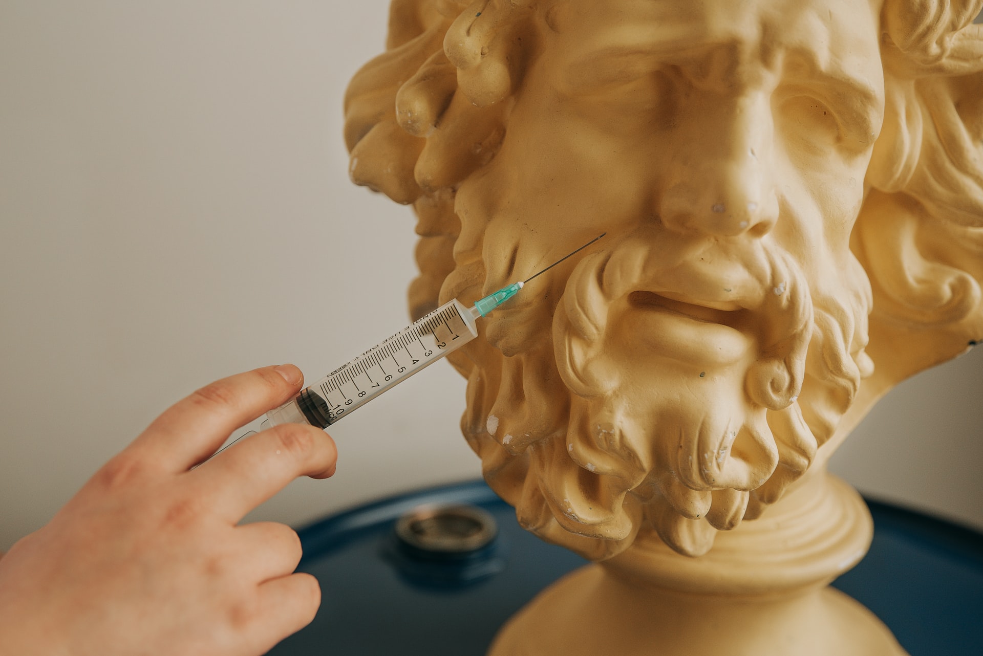 hand holding a needle to a statue with a pained expression