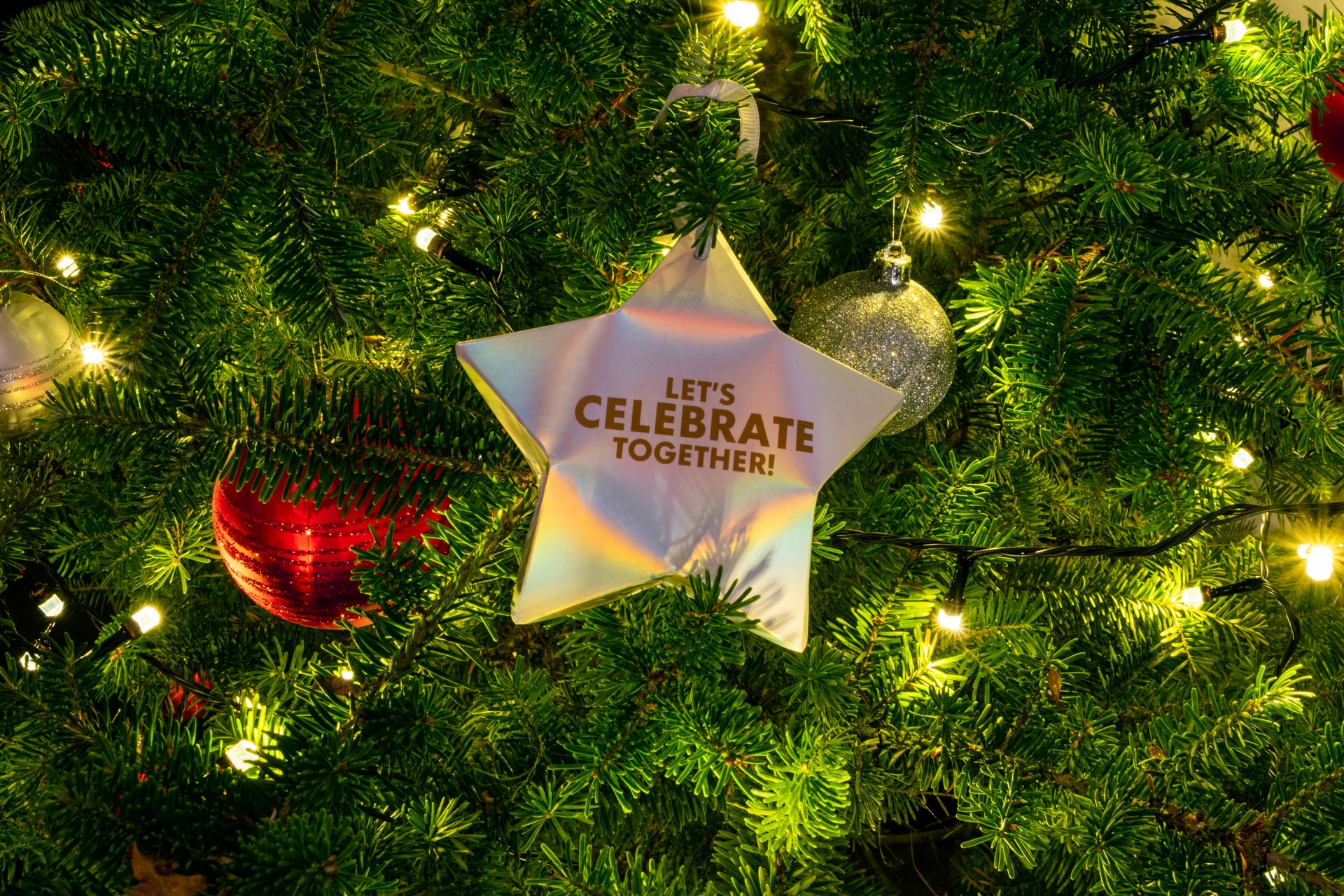 Gold star in a Christmas tree that reads 'let's celebrate together'