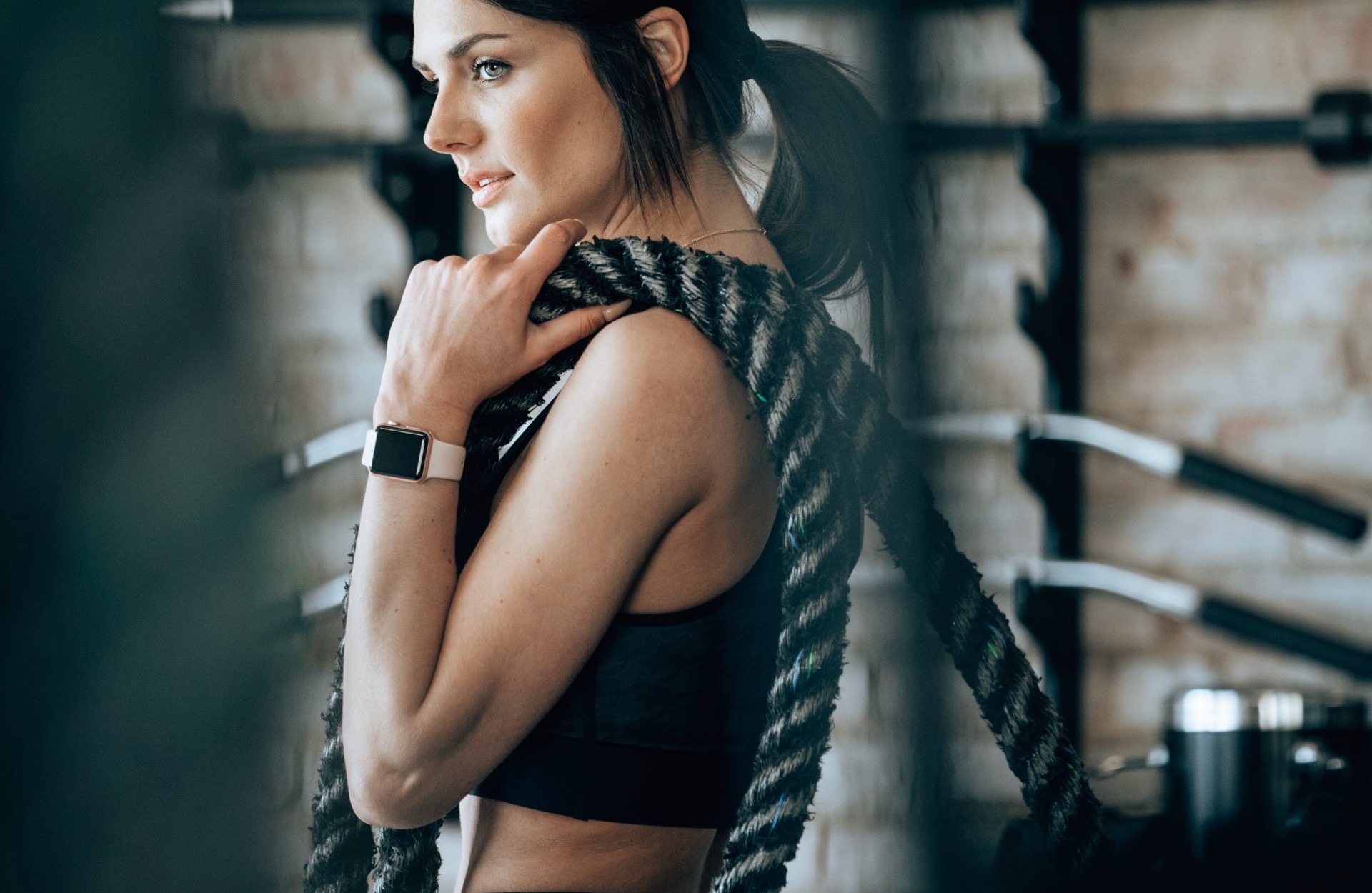 person in great shape holding rope over shoulder in a gym