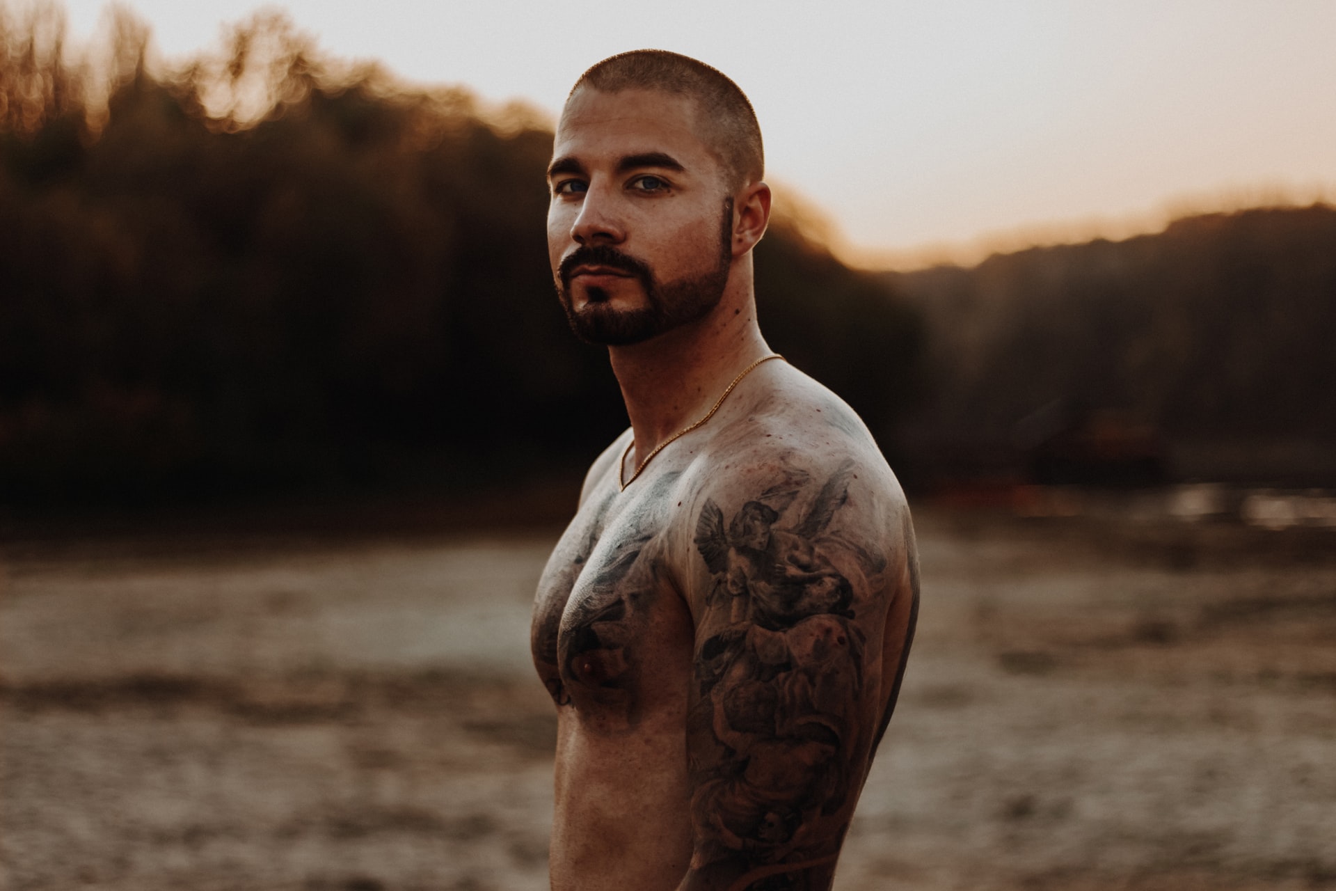 topless man with defined pectoral muscles looks at camera