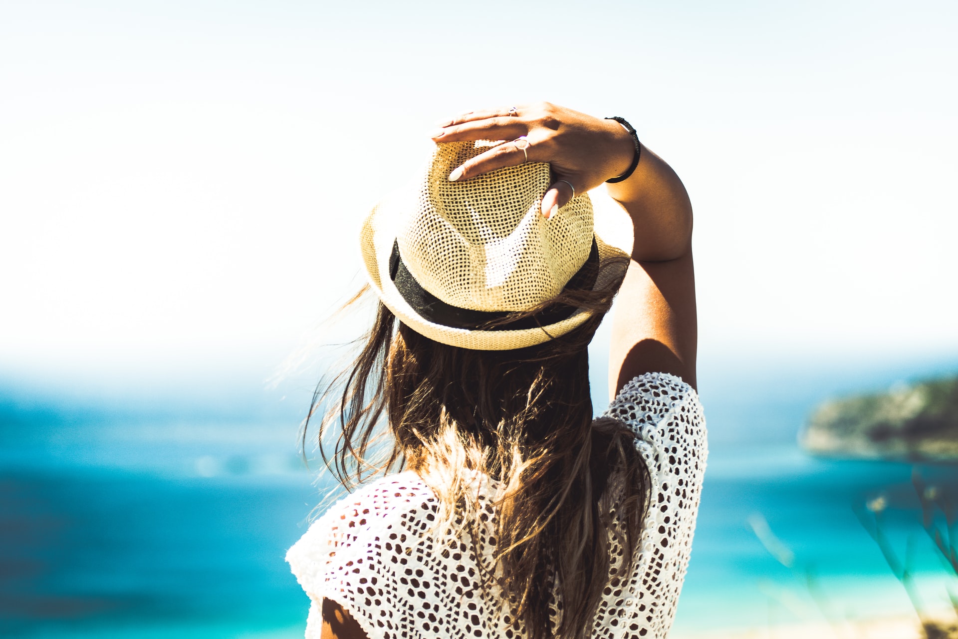 view of person from behind, hand on head, looking out to sea in the summer sun, does sun affect acne