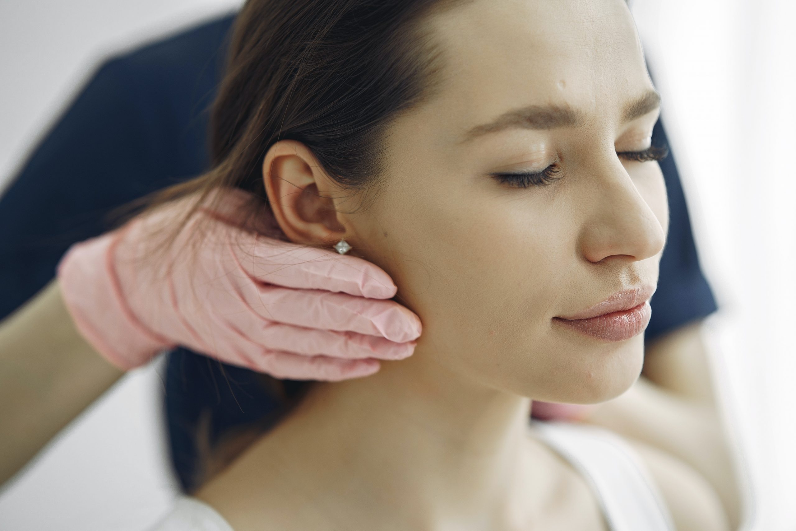 woman with eyes closed has her glands checked by professional