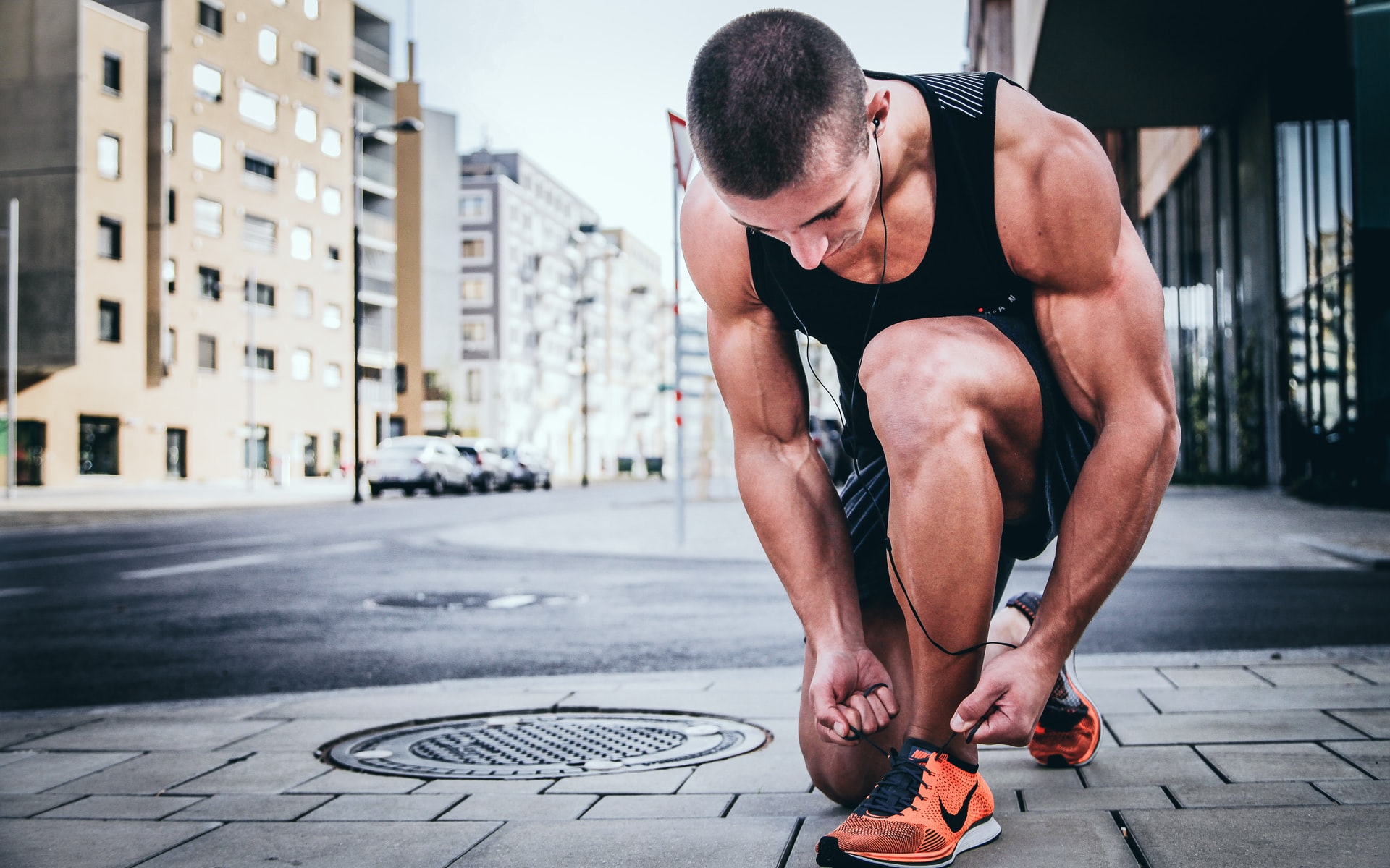 fit and healthy person crouched down in empty street, tying shoelaces ready for exercising