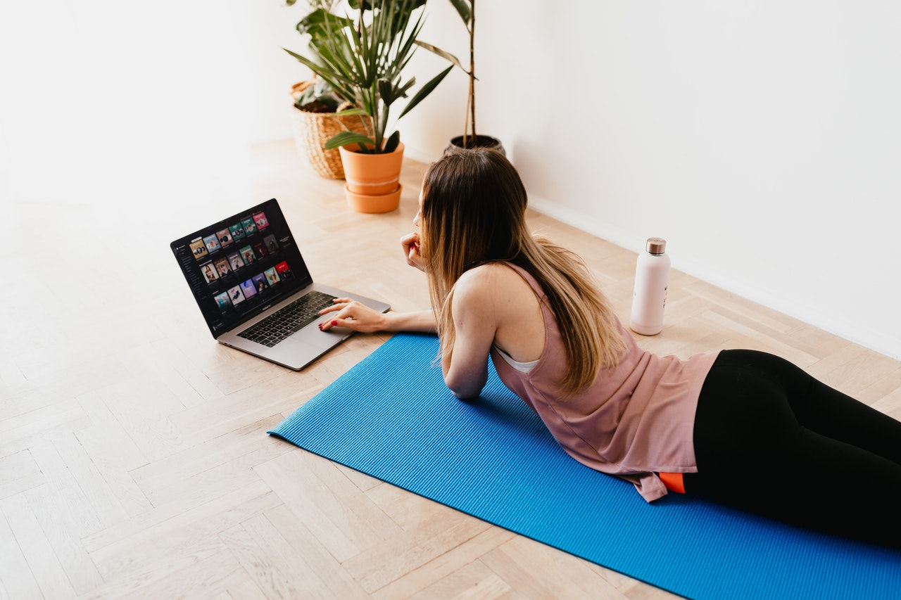 healthy person lying on exercise mat, looking at laptop, how to stay healthy, winter