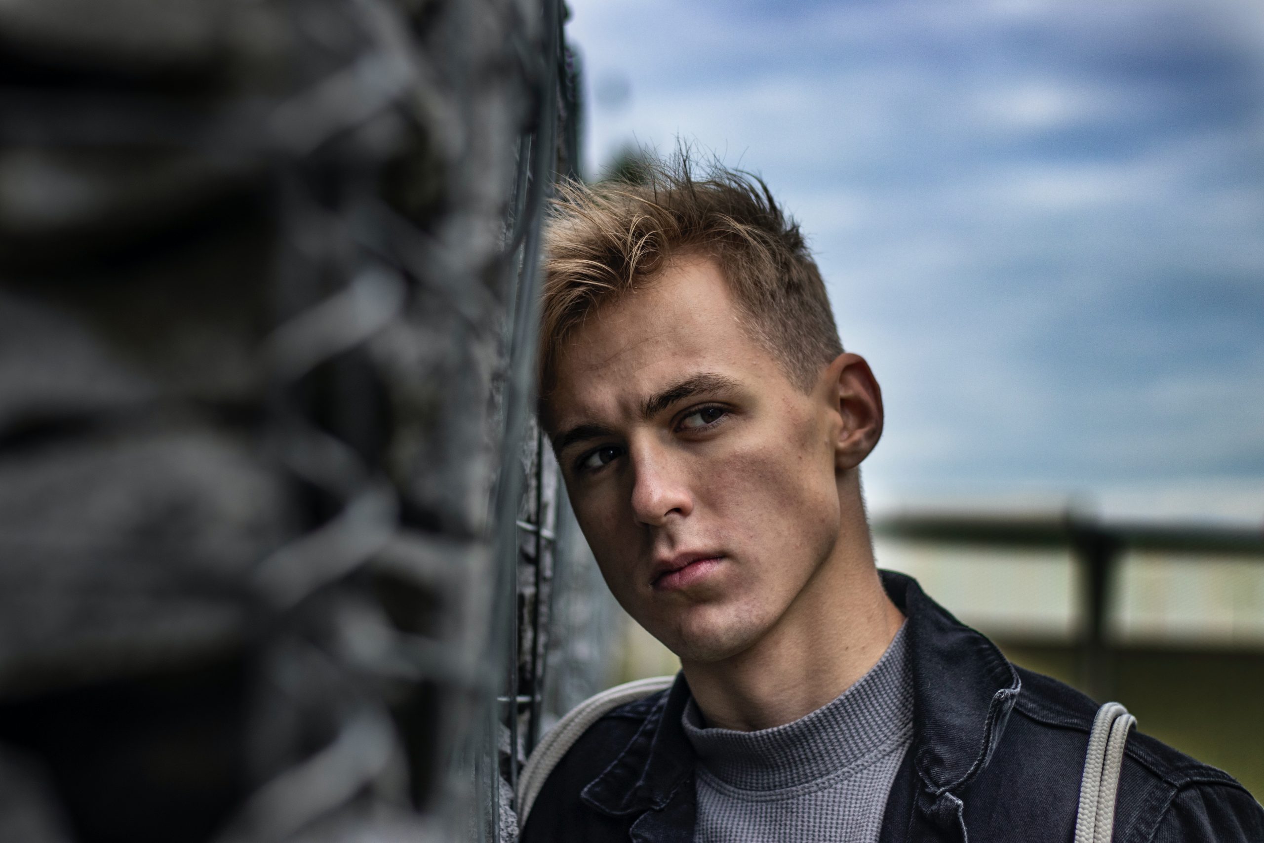 man leaning against fence outside