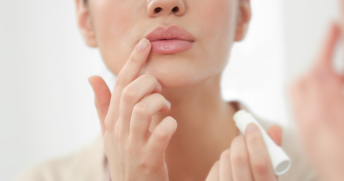 Woman applying lip balm in the mirror