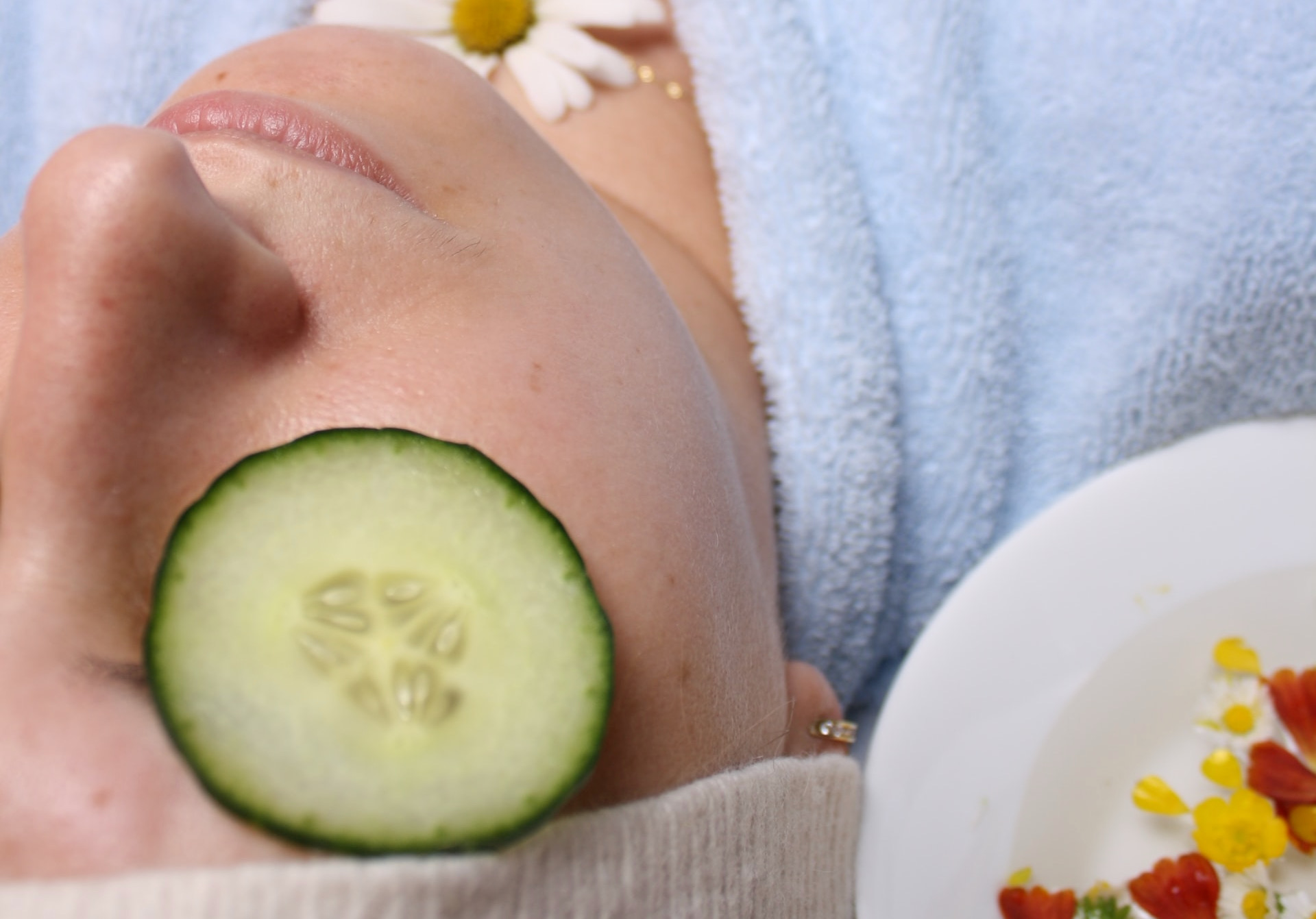 closeup of person lying down with cucumber slice on eye, reasons you need eye cream