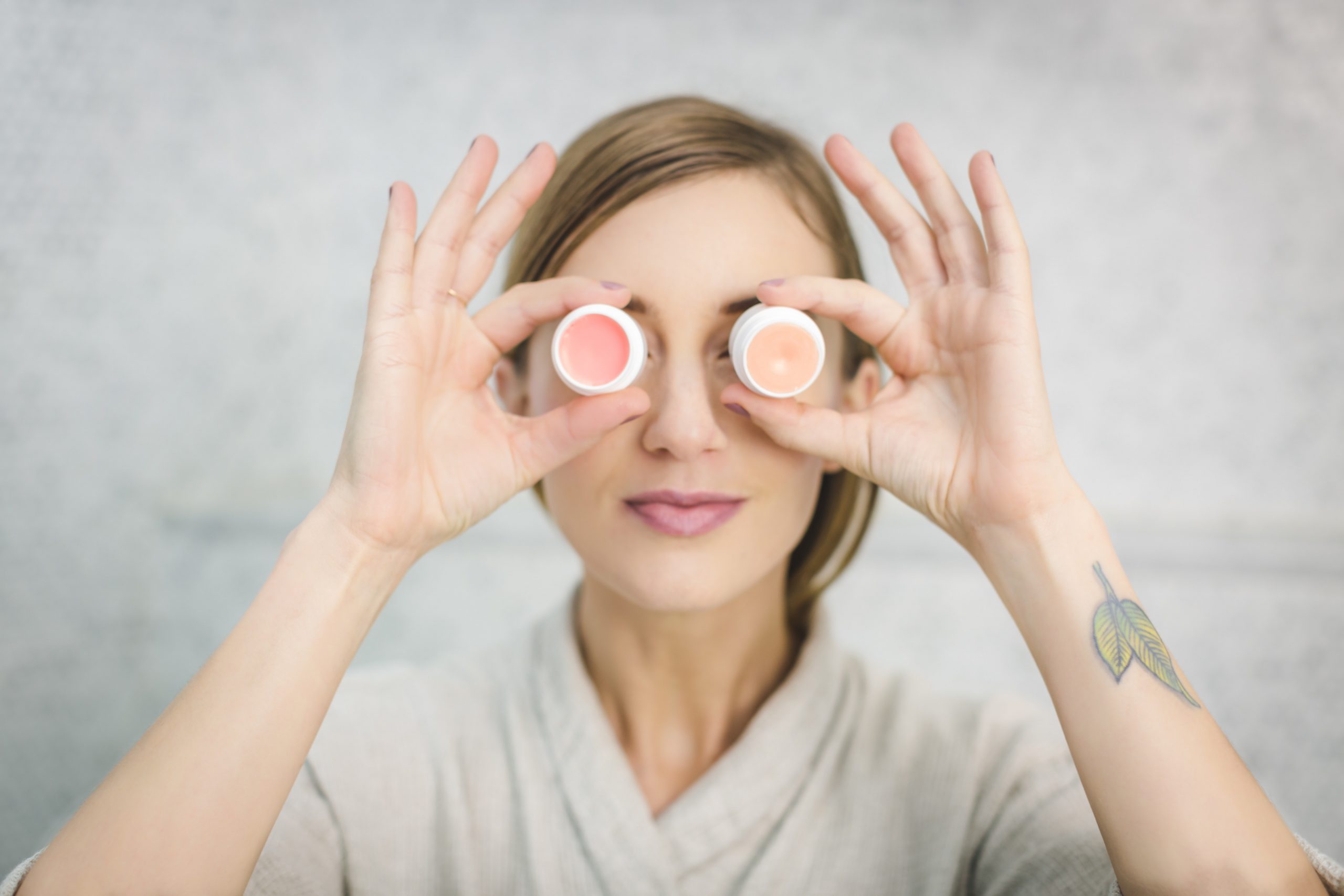 woman holding skincare products against her eyes