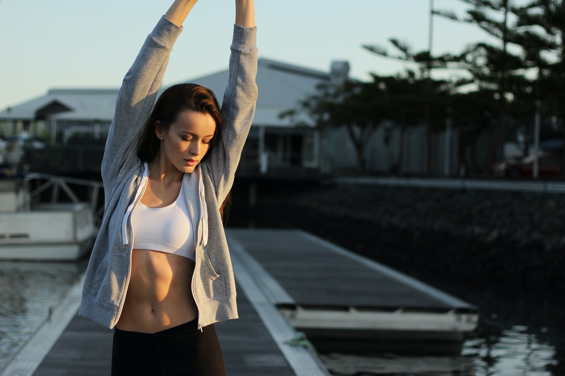 person standing outside, stretching and showing off flat stomach