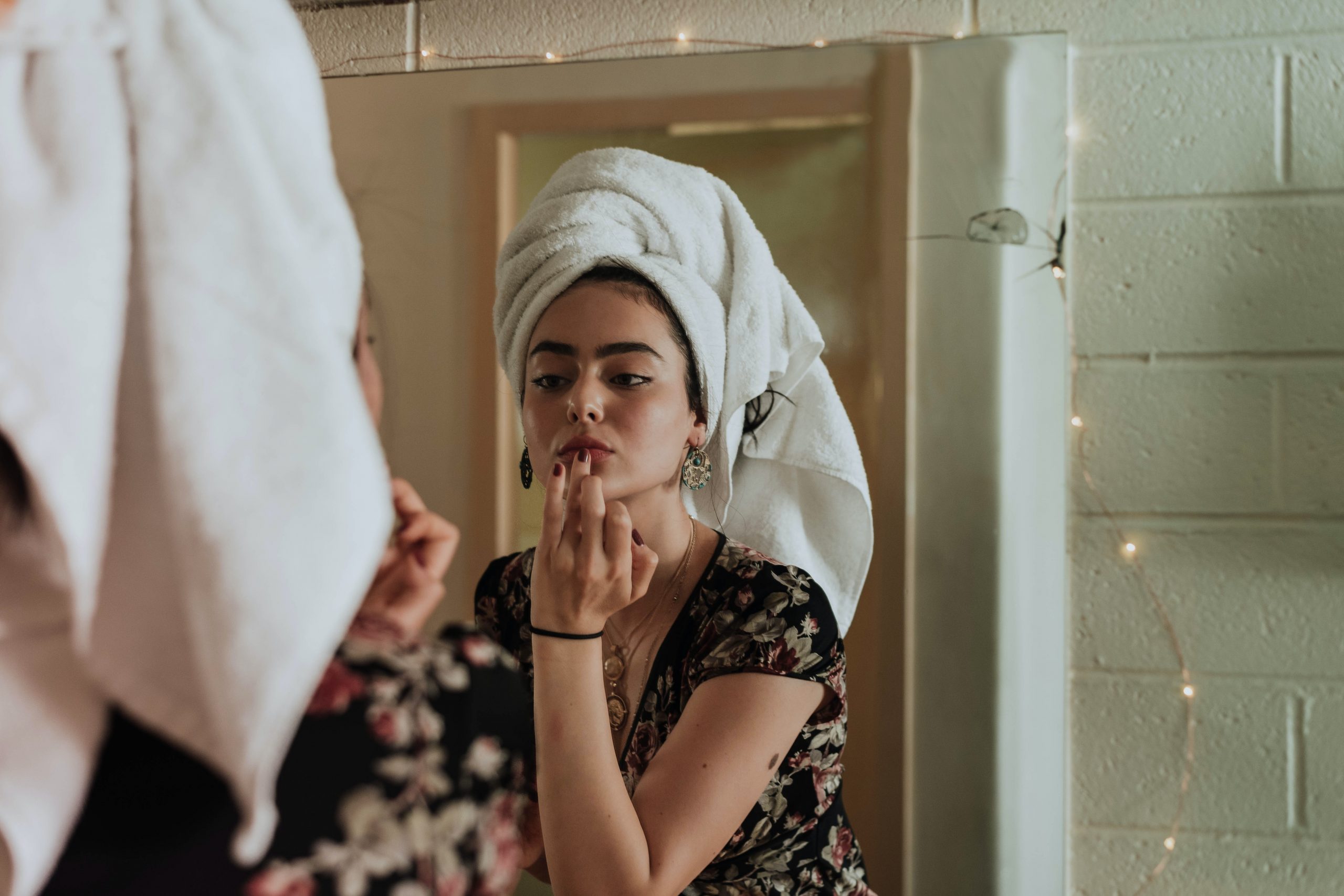 woman wearing towel on head looking in mirror, beauty