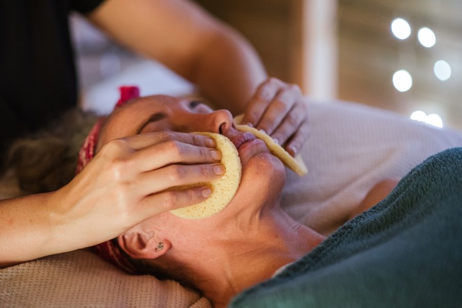 person receiving chemical peel has face washed by medical practitioner