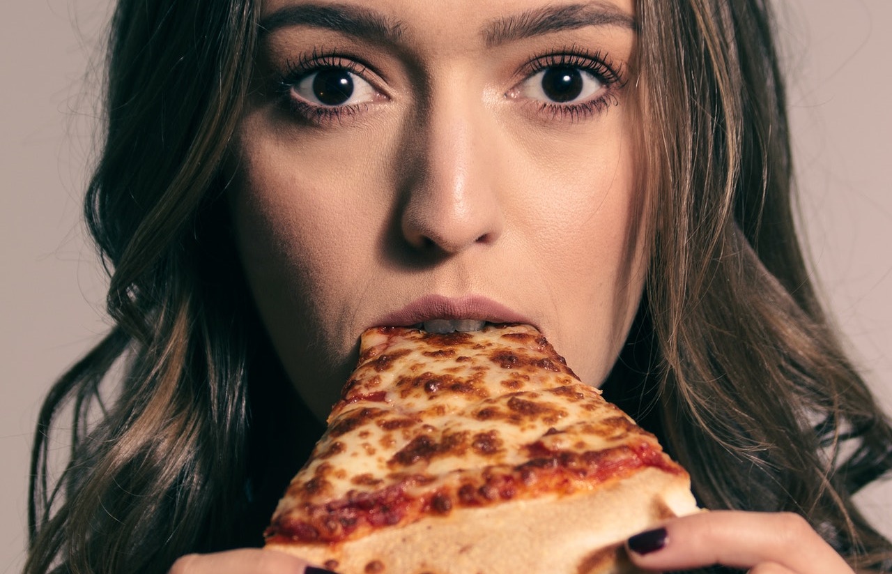 closeup of person eating a slice of pizza