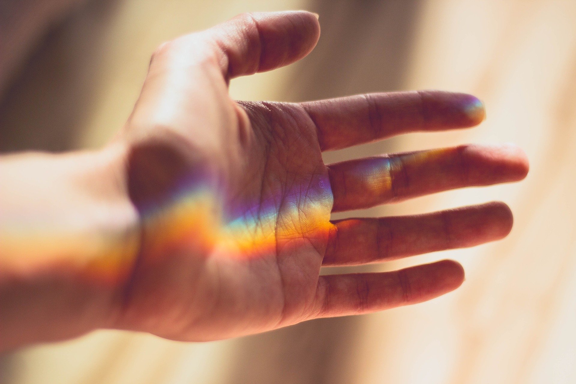 closeup of person's hand in beam of light, rainbow effect, anti-ageing for hands